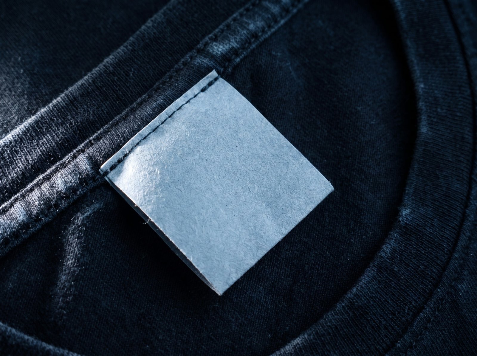 A small pale panel stitched flat against the dark inner seam of a shirt.