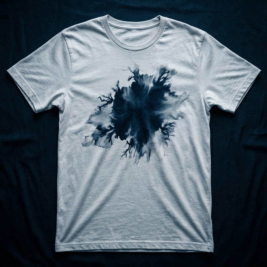 Drop 001, First Bleed: a pale cotton shirt carrying one large ink bloom soaked through the chest, its edge branching into fine tendrils.